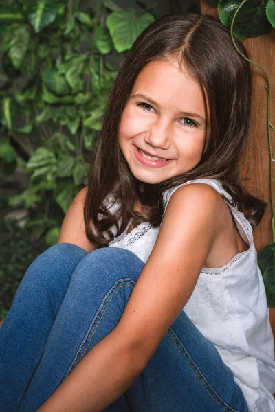 Portrait of a little girl sitting in the flowered garden — Stock Photo, Image