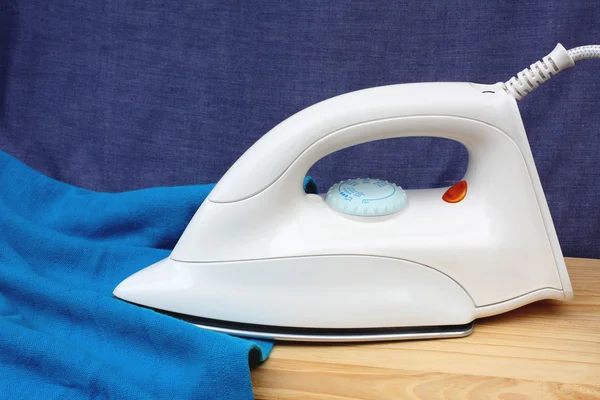 Electric iron and shirt, on white and blue background — Stock Photo, Image