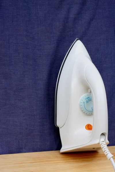 Electric iron on blue cloth background — Stock Photo, Image