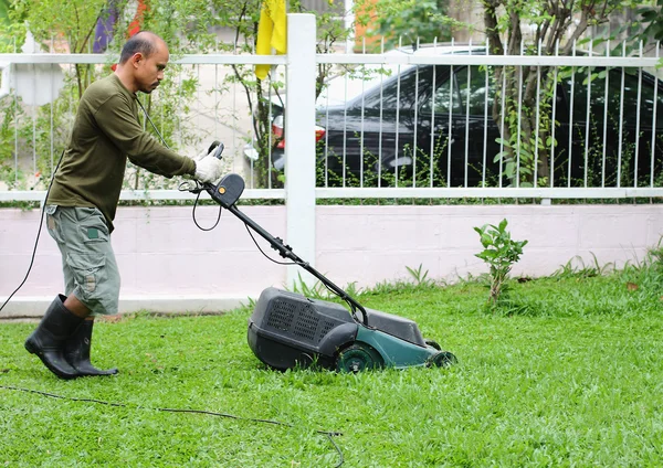 Hombre cortando hierba. Con la segadora . — Foto de Stock