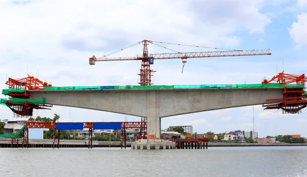 Construction crane at the bridge over the river — Stock Photo, Image