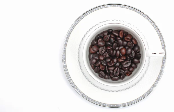 Grains de café dans un verre sur fond blanc. — Photo