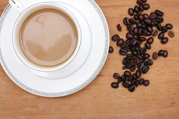 Chicchi di caffè con caffè. fondo di legno — Foto Stock