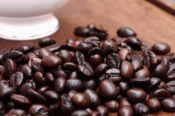 Kávová zrna s kávou. dřevěné pozadí — Stock fotografie