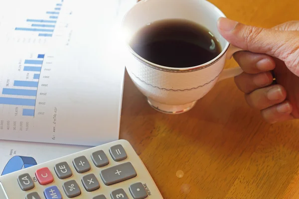 Hand som håller en kopp kaffe på ett träbord — Stockfoto