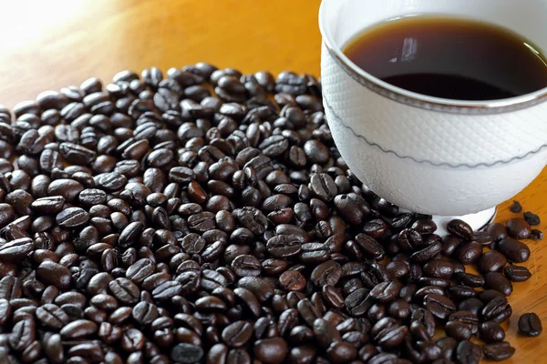 Tazza di caffè e chicco di caffè su un tavolo di legno — Foto Stock