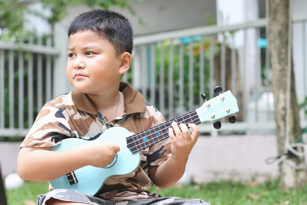 Chlapec hraje na ukulele zábavu. — Stock fotografie