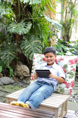 Asyalı çocuk tablet parkta oynarken