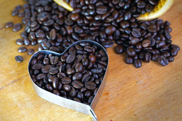 Granos de café en forma de corazón sobre mesa de madera — Foto de Stock
