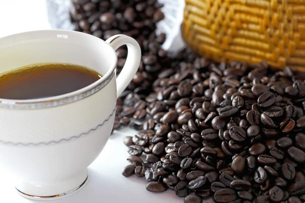 Chicchi di caffè e tazza di caffè su sfondo bianco — Foto Stock