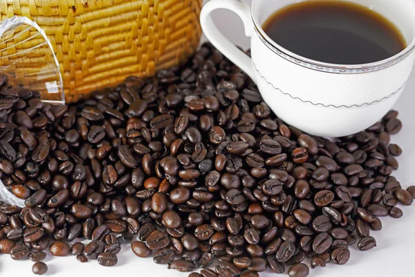 Grãos de café e xícara de café no fundo branco — Fotografia de Stock