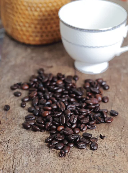 Šálek kávy a kávových zrn na dřevěný stůl — Stock fotografie