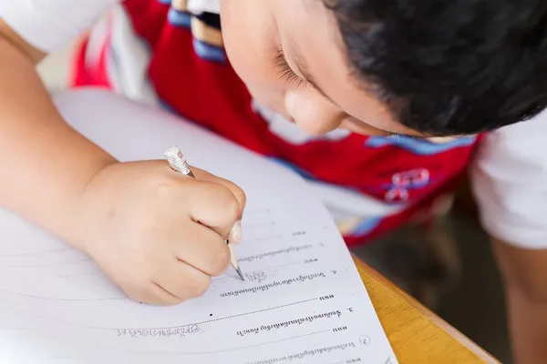 Le garçon travaille soigneusement ses devoirs . — Photo