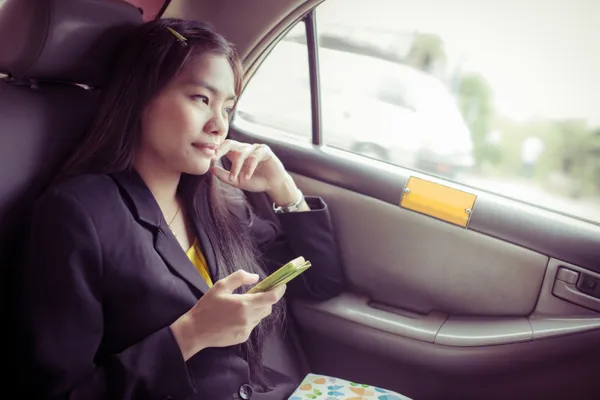 Hermosas mujeres de negocios asiáticas jóvenes utilizando un teléfono inteligente en el coche — Foto de Stock