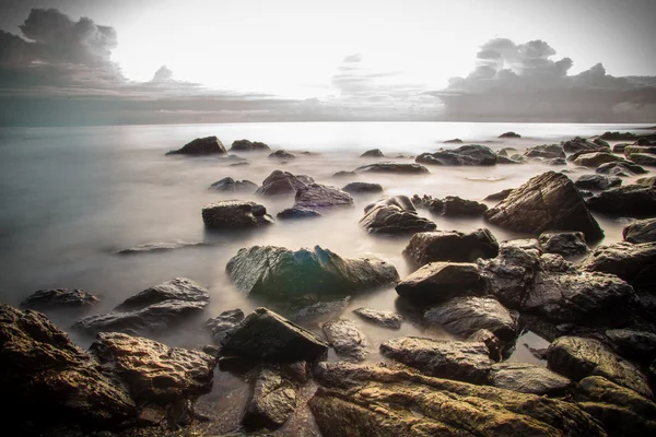 Playa con muchas rocas. Puesta de sol — Foto de Stock