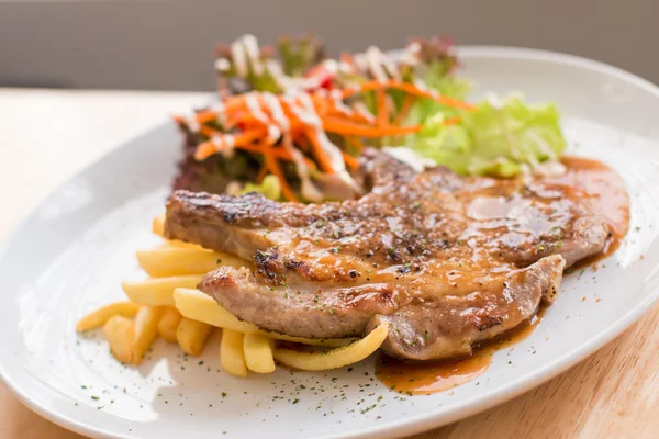 Steak de porc et frites garnies de sauce — Photo