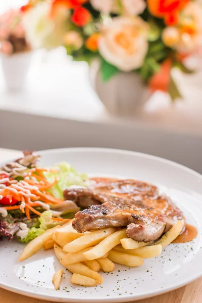 Steak de porc et frites garnies de sauce — Photo