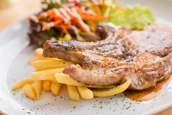 Varkensvlees biefstuk en Franse frietjes gegarneerd met saus — Stockfoto