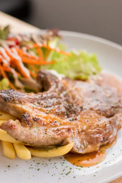 Varkensvlees biefstuk en Franse frietjes gegarneerd met saus — Stockfoto