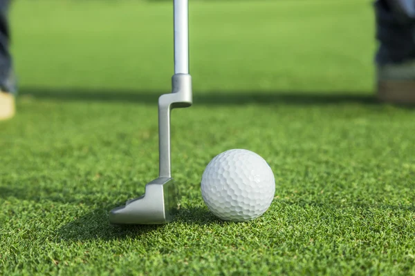 Інструктор кладе м'яч для гольфу в отвір на зеленому полі для гольфу — стокове фото