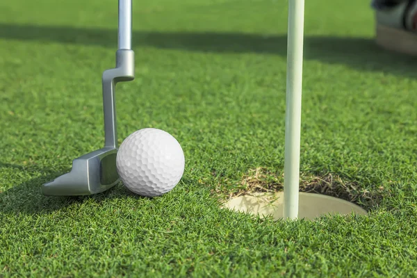 Інструктор кладе м'яч для гольфу в отвір на зеленому полі для гольфу — стокове фото