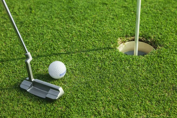 Putter coloca uma bola de golfe para buraco no verde do campo de golfe — Fotografia de Stock