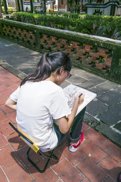 Особняк Бен-Юань Лин и вид на сад, одна девушка сидит на стуле и рисует дерево на бумаге карандашом — стоковое фото
