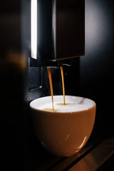 Kahve makinesi sarı bir fincana kapuçino hazırlar ve koyar. Makineden mis kokulu kahve..