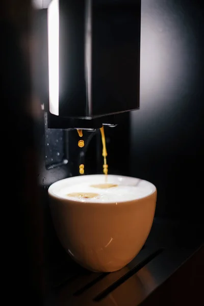 Kahve makinesi sarı bir fincana kapuçino hazırlar ve koyar. Makineden mis kokulu kahve..