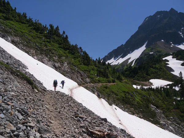 妇女背包徒步横跨雪场 — 图库照片