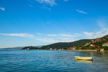 Karadağ 'ın Durici kentinde kıyıya yakın bir yerde demirli küçük bir tekne bulunuyor. Kotor Körfezi 'nin etrafındaki yolun kenarından sakin bir yaz manzarası.