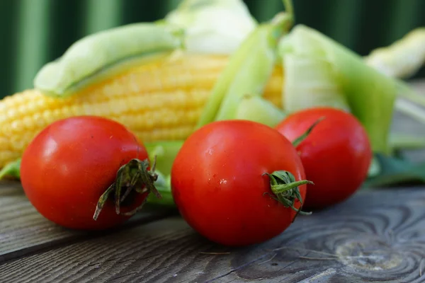 Tři červené cherry rajčata s jedním kukuřičné paličky a dva hráškových lusků — Stock fotografie