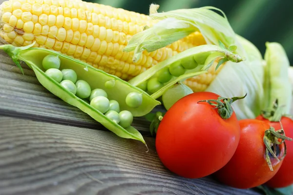 Three red cherry tomatoes with one corn cob and two pea pods — Stock Photo, Image