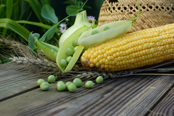 Still life with peas, corn, onion, ears of wheat and a straw hat — Stock Photo, Image