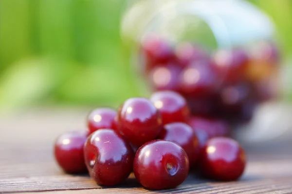 Cereza mojada sobre una plancha de madera sobre un fondo verde borroso — Foto de Stock