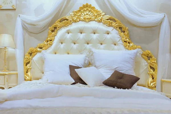 Lyxiga Queen size-säng med guld-mönstrad huvudgavel — Stockfoto