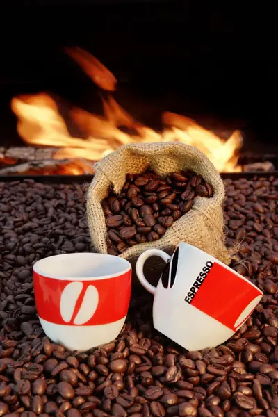 Две чашки эспрессо и кофейных зерен на фоне огня — стоковое фото
