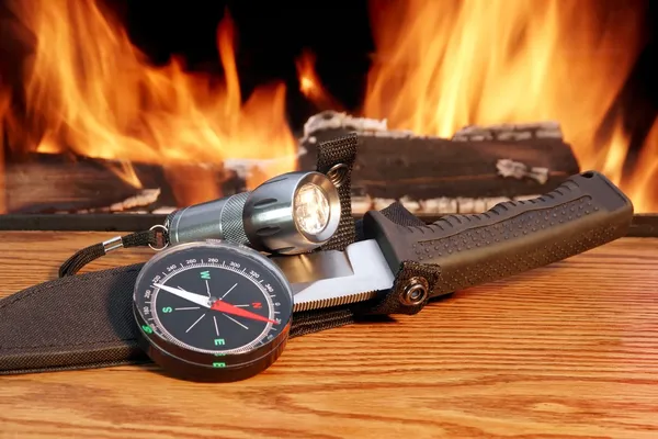 Compass, a hunting knife and a handheld flashlight around the ca — Stock Photo, Image