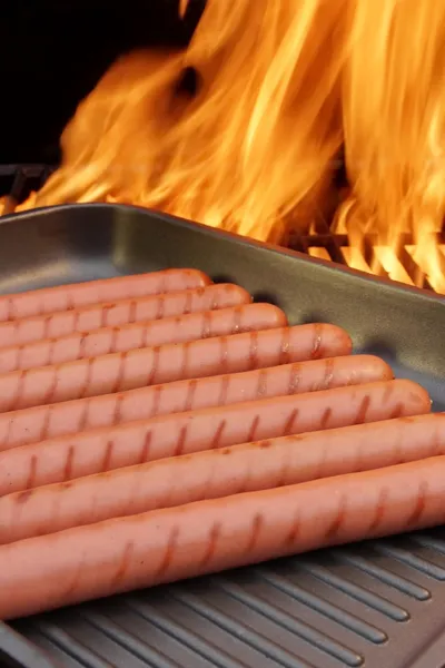 Grilled sausages on frying pan and BBQ Grill in background, XXXL — Stock Photo, Image