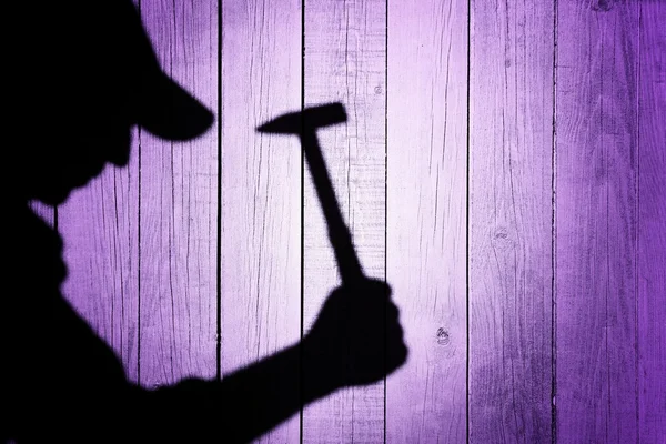 Ombra di un uomo con martello su sfondo di legno naturale — Foto Stock