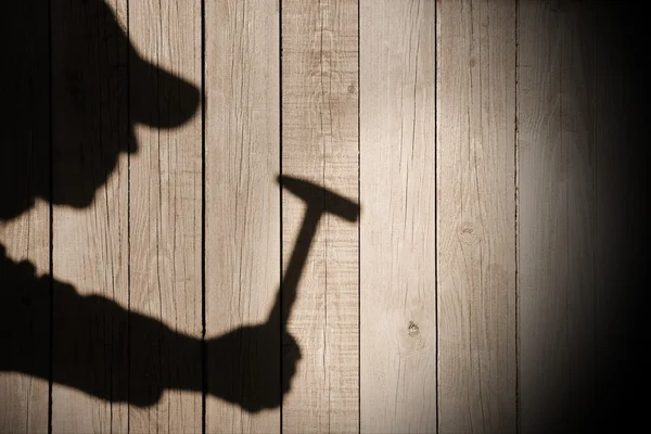 Sombra de un hombre con martillo sobre fondo de madera natural —  Fotos de Stock