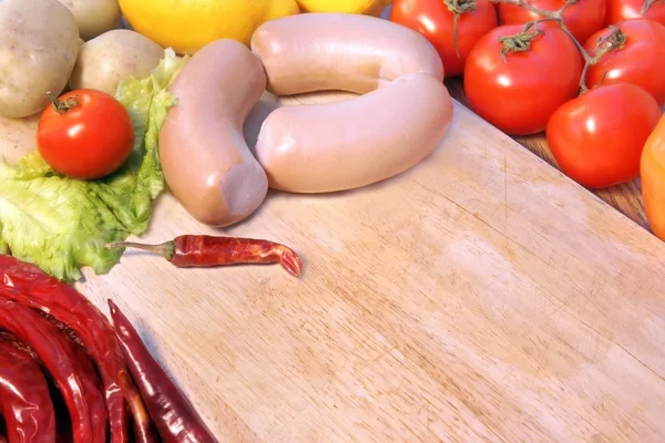 Ahşap kesme tahtası üzerinde sebze ve çiğ sosis — Stok fotoğraf