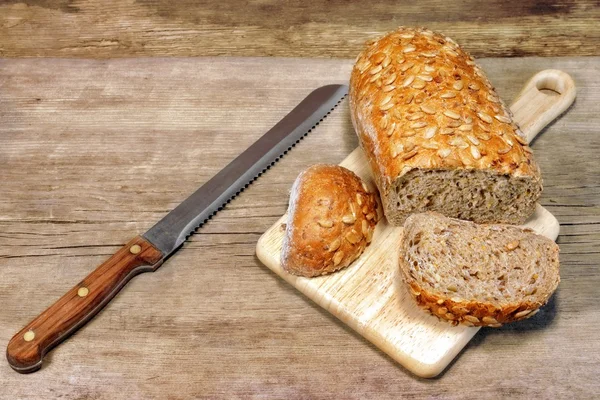 Pain de céréales pain avec des grains et couteau trancheuse dans rustique encore l — Photo