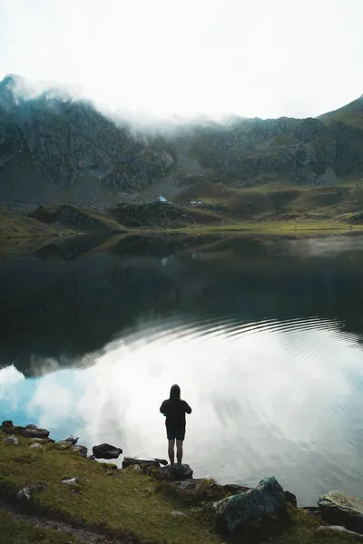 Kapüşonlu bir adam Ayous Gölü, Pyrenees 'de akıllı telefonuyla fotoğraf çekiyor.