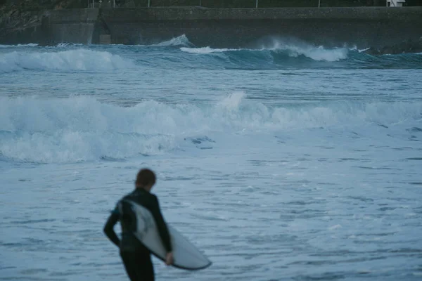 Blurry young surfer running in front of the ocean during sunset