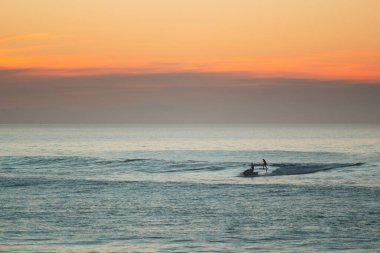 Jet ski towing a foil surfer during the sunset on atlantic ocean