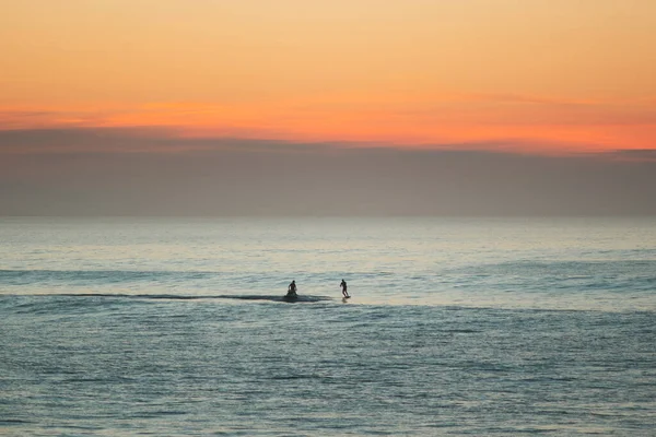 Jet ski towing a foil surfer during the sunset on atlantic ocean