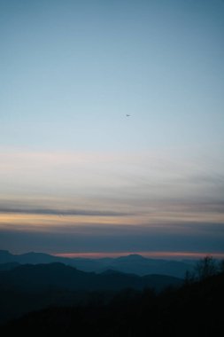 Bask Ülkesi 'nde gün batımında bulutların üzerinde uçan uçak.