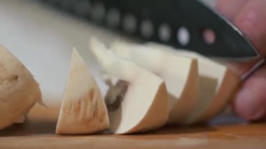 Ev ya da restoranın mutfağında yakın çekim. Şef, şampiyonları sağlıklı yemek için bıçakla dilimlere ayırıyor. Lezzetli öğle ya da akşam yemeği için malzemeler hazırlanıyor..