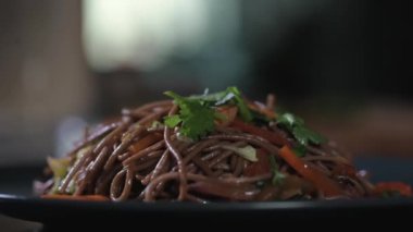 Erkek şef lezzetli şehriye yemeğini taze sebzeler, otlar ve baharatlarla süslüyor. Ev ya da restoranın mutfağında yemek pişirmek. Restoranda öğle yemeği. Pan-Asya yemekleri.